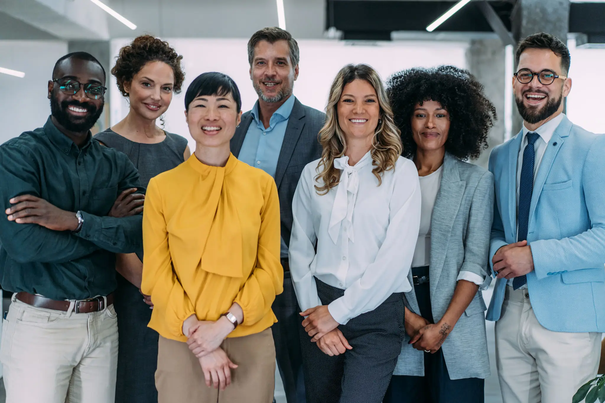 A diverse group of smiling professionals standing together in an office.